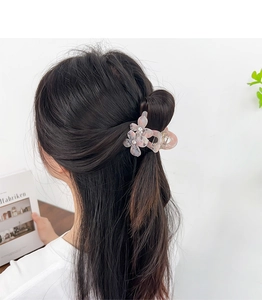 Détail de la pince à cheveux fleur rose avec strass sur la coiffure du modèle