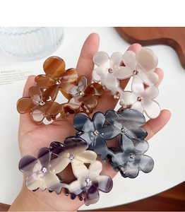 Détail de quatre pinces à cheveux florales en acétate avec des centres en strass brillants