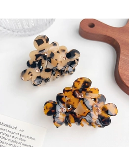 Détail de pinces à cheveux fleur en acétate avec motif écailles et centres diamants