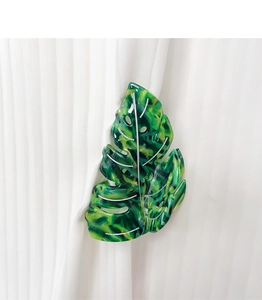 Detail of green leaf hair claw clip with marble texture and silver veins on white fabric