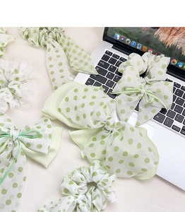 Detail of light green floral hair scrunchies and bow clips with pearl and lace accents