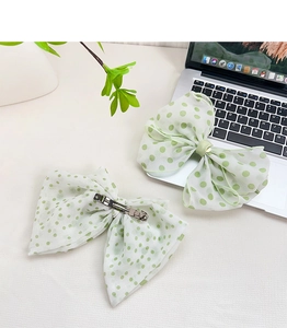 Detail of green and white polka dot chiffon bow hair clips with silver metal duckbill clip