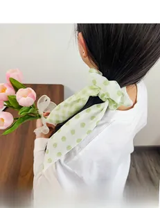 Detail of mint green floral hair scrunchie with ribbons styled on a ponytail hairstyle