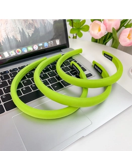 Three bright green sponge headbands with handmade labels on a silver laptop keyboard