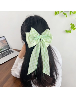 Gros plan d'un nœud à cheveux à carreaux vert menthe avec perle et longs rubans
