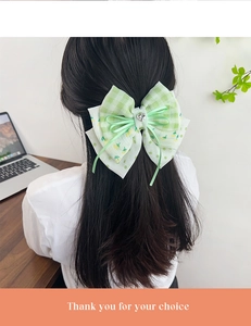 Détail du nœud papillon à carreaux verts avec strass cœur sur les cheveux