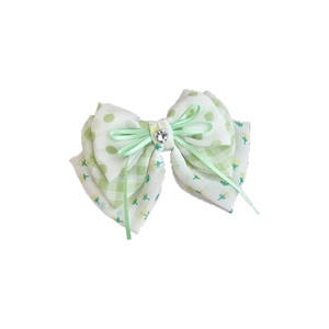 Green floral bow hair clip with polka dots and crystal heart on white background