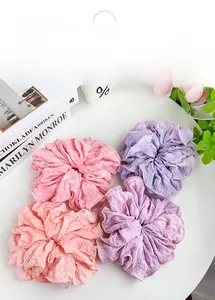 Close-up of pleated scrunchies in pastel pink and lilac tones on a white aesthetic background