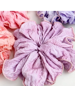 Close-up of oversized pleated fabric hair scrunchies in soft gradient pastel colors