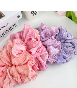 Macro shot of oversized pink and purple pleated fabric scrunchies with ruffled texture