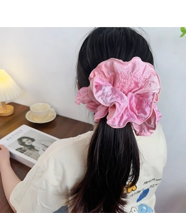 Close-up of a pink pleated fabric scrunchie styled on a ponytail for an elegant look