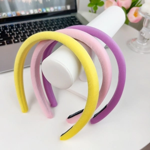 Three colorful handmade padded sponge headbands in yellow, pink and violet on a desk