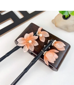 Detailansicht chinesischer Haarstäbe mit durchscheinenden rosa Blüten und Perlenverzierung
