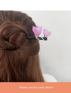 Detailaufnahme von lila Harz-Magnolienblüten und weißen Perlen auf einem Haarstab aus Holz