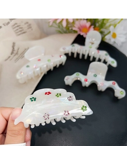 Macro detail of iridescent acetate hair claw clips with colorful rhinestone flower patterns