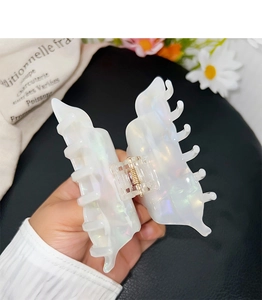 Detailed macro view of pearlescent acetate hair claw clip with iridescent finish and metal spring
