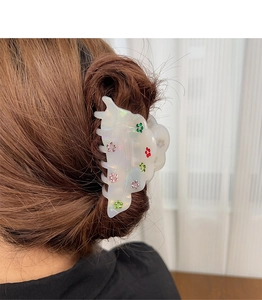 Detailed view of iridescent acetate hair claw clip with colorful rhinestone flower accents