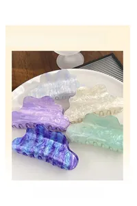 Détail de cinq pinces à cheveux en acétate en forme de nuage avec texture marbrée sur plat