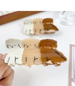 Detailed shot of cute acetate puppy hair clips in cream and brown with Ideal Cycle text