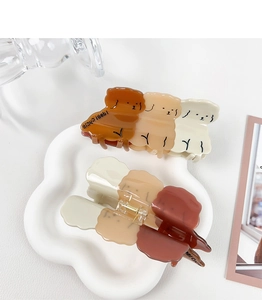 Close-up of three teddy dog hair claws in brown tones made of glossy acetate material