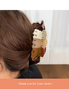 Detail view of brown teddy bear hair claw clips worn on dark wavy hair for styling