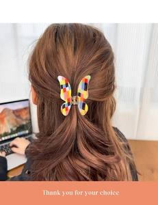 Pinza per capelli a farfalla colorata con motivo a scacchi su capelli lunghi castani mossi