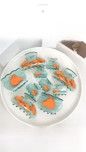 Détail de pinces à cheveux turquoise en acétate avec motifs de poissons orange divers