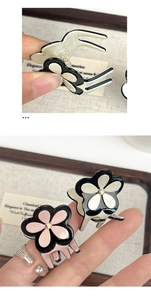 Detailed close-up of small acetate clover hair claws with rhinestones in black and pink