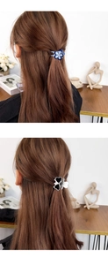 Detail view of acetate four-leaf clover and heart hair claws in a half-up hairstyle