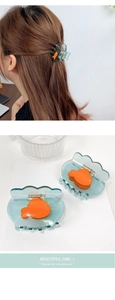 Vue détaillée de la pince à cheveux bleue translucide avec un motif de poisson orange