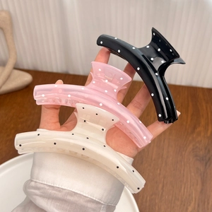 Drei große gepunktete Haarklammern in Schwarz, Rosa und Beige in der Hand gehalten