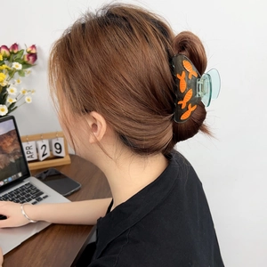 Pince à cheveux en acétate avec motif poisson orange portée sur des cheveux longs