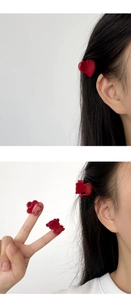 Detailed view of red resin hair clips in heart, cat, and flower shapes on dark hair