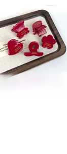 Close-up of burgundy acetate mini hair clips in bear and heart shapes on a wood tray