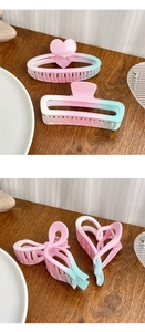 Detailed view of pink and blue gradient hair claws in heart and bow shapes on wood