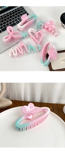Detail view of pink and green gradient hair claws in floral and heart shapes