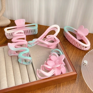 Pink and mint green gradient matte hair claw clips set in various shapes on a wooden tray