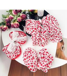 Macro shot of red floral fabric hair scrunchies with lace and pearl details