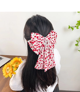 Detail of floral bow hair clip with red rose pattern and beaded tassel on long hair