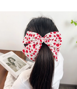 Close-up of white oversized bow hair tie with red floral pattern on model back view