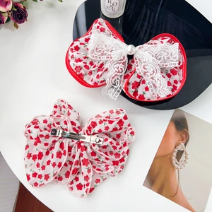 Floral print hair bow clips with lace layers and large pearl accents on white background