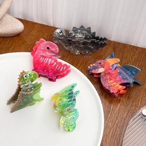 Five colorful acrylic dinosaur hair claws with marble texture on a white plate