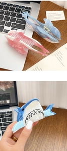 Detail of shark-shaped acetate hair claws in blue and pink with a pearlescent finish