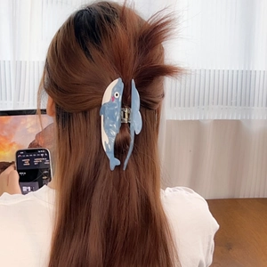 Blue and white whale-shaped acetate hair claw clip worn on a woman's long hair