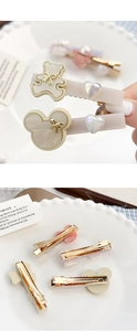 Detail van crème haarclips in de vorm van een beer met gouden strikken en metalen klem
