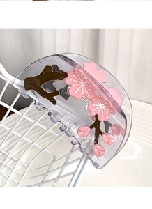 Makro-Detail einer Pflaumenblüten-Haarklammer aus Acetat mit Blumenmuster auf weißem Netz