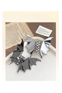 Detailed view of silver and black metal bat wing hair claws with a polished chrome finish