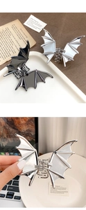 Detailed macro view of large metal bat-shaped hair claws in black and silver finishes