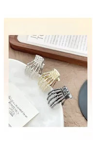 Détail des pinces à cheveux en forme de main de squelette en métal doré, argent et noir