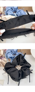 Détail d'un chouchou en satin élastique avec rubans en noir, bleu et beige clair